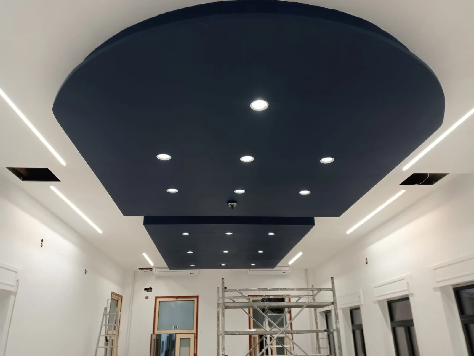 Controsoffitto geometrico blu con faretti e linee luminose